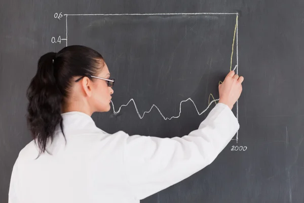 黒板には、グラフを描く暗い髪の科学者 — ストック写真