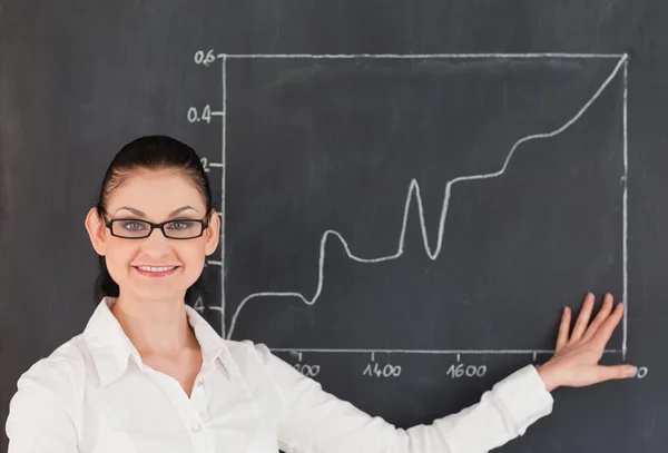 Scientist showing charts while standing near the blackboard — Stock Photo, Image