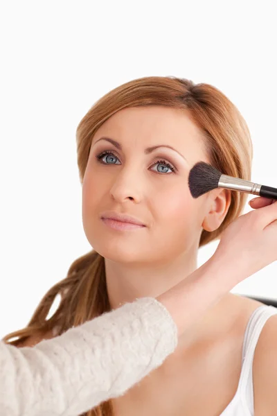 Maquiagem artista aplicando maquiagem para uma mulher atraente — Fotografia de Stock