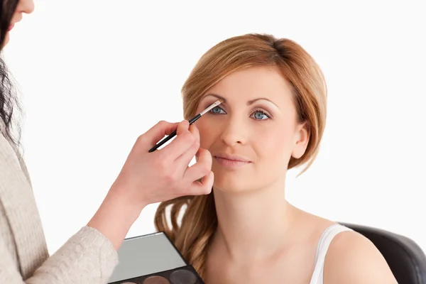 Maquiagem artista aplicando maquiagem para uma mulher bonita — Fotografia de Stock