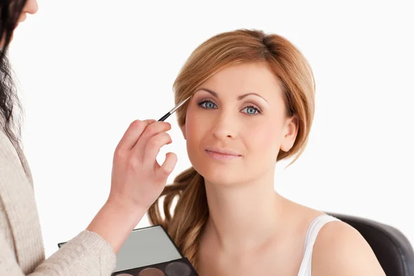 Maquiagem artista aplicando maquiagem para uma mulher loira — Fotografia de Stock
