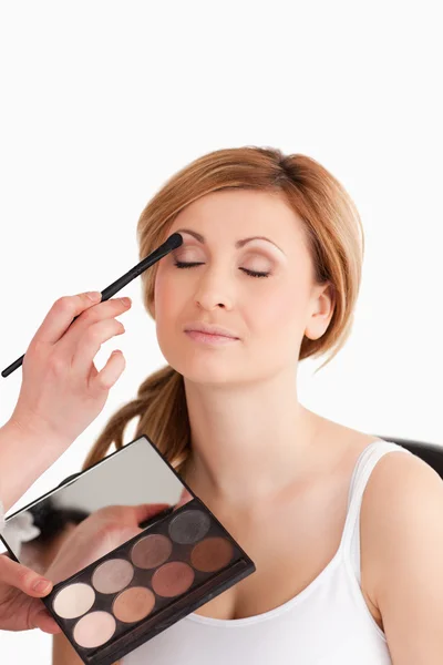 Maquiagem artista aplicando maquiagem para uma jovem mulher — Fotografia de Stock