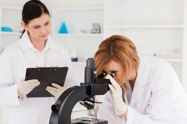 Blond-haired scientist and her assistant conducting an experimen — Stock Photo, Image