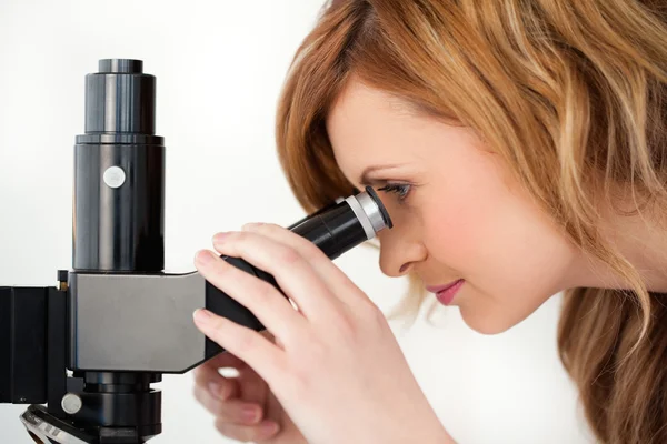 Sarı saçlı bilim adamı bir mikroskop ile seyir — Stok fotoğraf