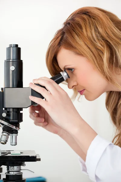 Χαριτωμένο ξανθιά μαλλιά επιστήμονας αναζητούν μέσα από ένα μικροσκόπιο — Φωτογραφία Αρχείου