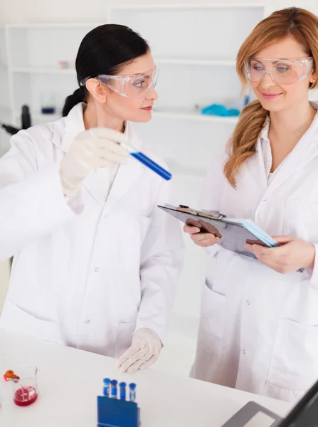 Dos científicos observando un tubo de ensayo azul — Foto de Stock