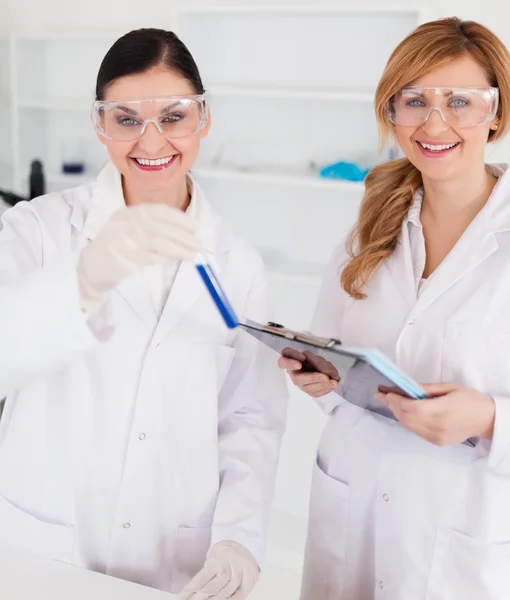Zwei Wissenschaftler schauen in die Kamera, während sie ein Reagenzglas in der Hand halten — Stockfoto
