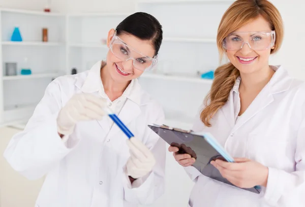 Zwei Wissenschaftler schauen in die Kamera, während sie ein Reagenzglas in der Hand halten — Stockfoto