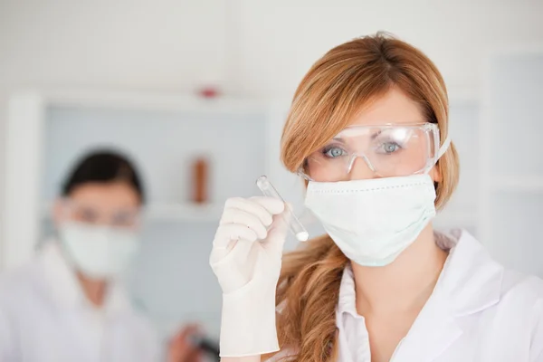 Blond-haired scientist holding a test tube looking at the camera — Stock Photo, Image