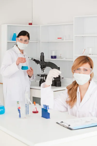 Ξανθά μαλλιά και μελαχρινός επιστήμονες που διεξάγει ένα πείραμα — Φωτογραφία Αρχείου