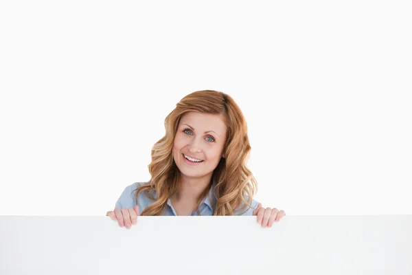 Lovely blond-haired woman standing behind an empty white board — Stock Photo, Image