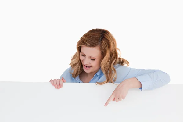 Attractive blond-haired woman standing behind a white board — Stock Photo, Image