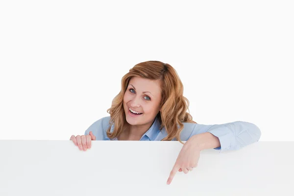 Happy blond-haired woman standing behind a white board — Stock Photo, Image