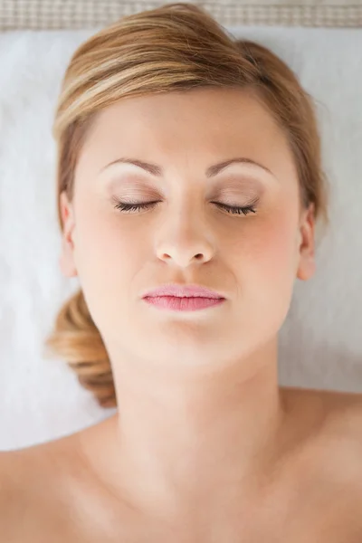 Young and pretty blond-haired woman lying down while receiving a — Stock Photo, Image