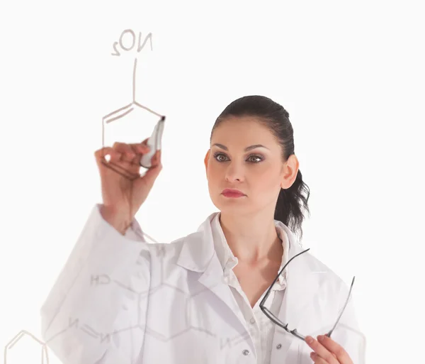 Dark-haired woman writting a formula on a white board — Stock Photo, Image