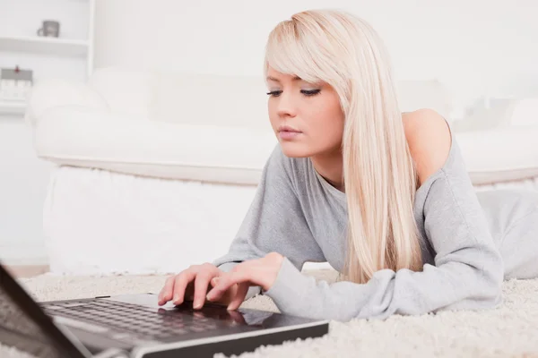 有魅力的金发碧眼女人放松躺在地毯上的笔记本电脑上 — 图库照片