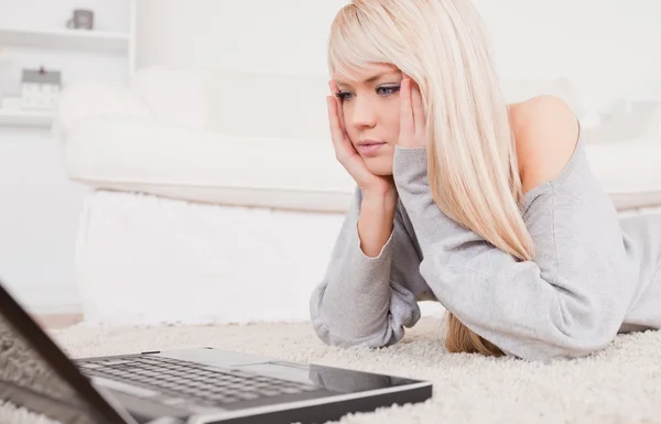 Atrakcyjna kobieta koncentrat na laptopa leżąc na karpia — Zdjęcie stockowe