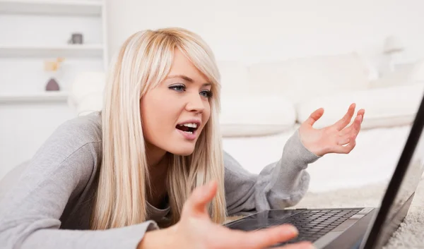 Vacker blond kvinna frustrerad med hennes dator som ligger på en ca — Stockfoto