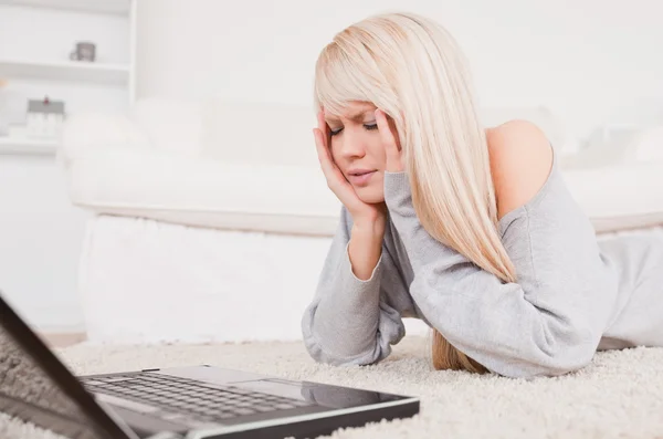 Mujer bastante concentrado relajarse en el ordenador portátil acostado en una alfombra —  Fotos de Stock