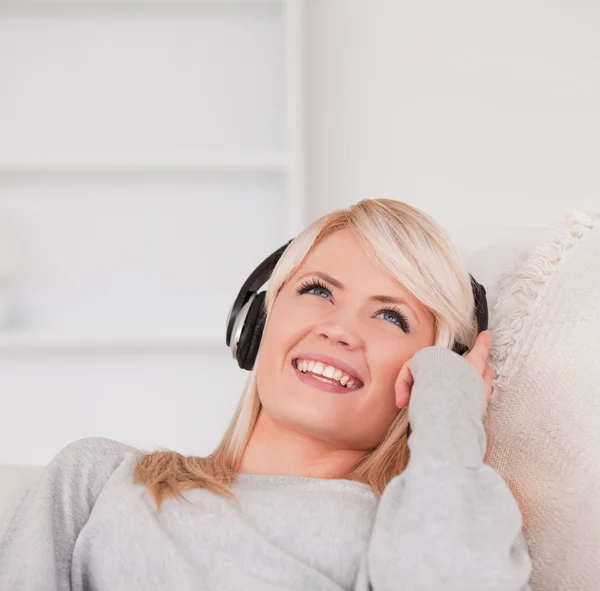 Ładny blond kobieta ze słuchawkami w sofę — Zdjęcie stockowe
