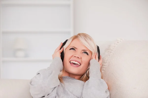 Piękne młode blond kobieta ze słuchawkami w sofę — Zdjęcie stockowe