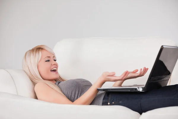 Χαλαρωτικό σε φορητό υπολογιστή που βρίσκεται σε ένα καναπέ και χαρούμενη γυναίκα — Φωτογραφία Αρχείου