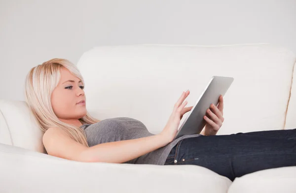 Hezká žena ležící na pohovce relaxační na lince tablet počítačů — Stock fotografie