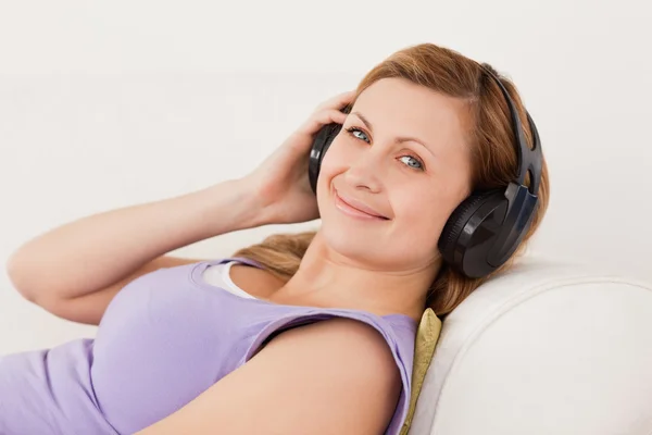 美しいブロンドの髪女性 sof に横たわっている音楽を聴く — ストック写真
