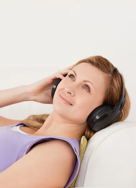 Söt blond kvinna lyssna på musik liggande på soffan — Stockfoto
