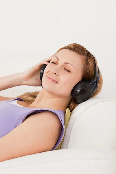 Ευτυχισμένη ξανθά μαλλιά γυναίκα, ακούγοντας μουσική που βρίσκεται στον καναπέ — Φωτογραφία Αρχείου