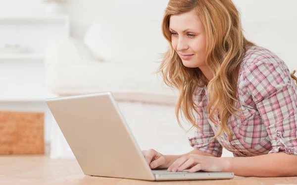 Blonďatí žena pracující na svém laptopu, vleže na podlaze — Stock fotografie