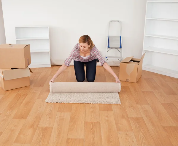 Blond kvinna rullar upp en matta att förbereda för att flytta hus — Stockfoto