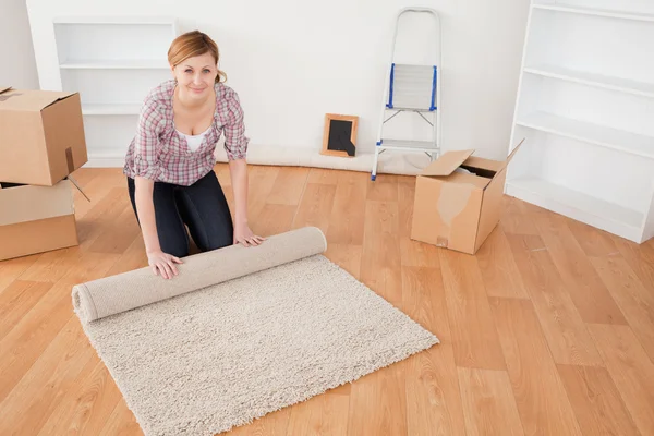 Aantrekkelijke vrouw oprollen van een tapijt te bereiden op het huis verplaatsen — Stockfoto