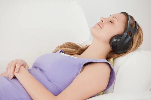 Glad blond kvinna lyssna på musik liggande på sof — Stockfoto