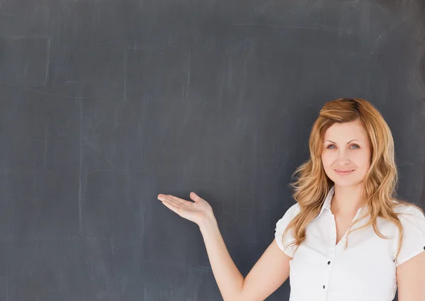 Cute female teacher showing an empty blackboard — Stock Photo, Image