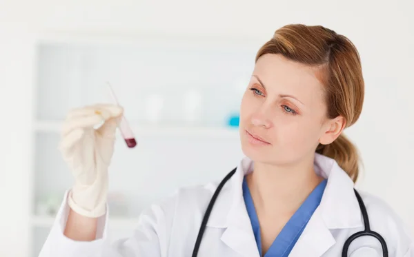Cientista feminina a olhar para um tubo de ensaio vermelho — Fotografia de Stock