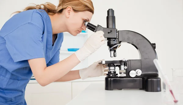 Жінка-вчена дивиться через мікроскоп — стокове фото