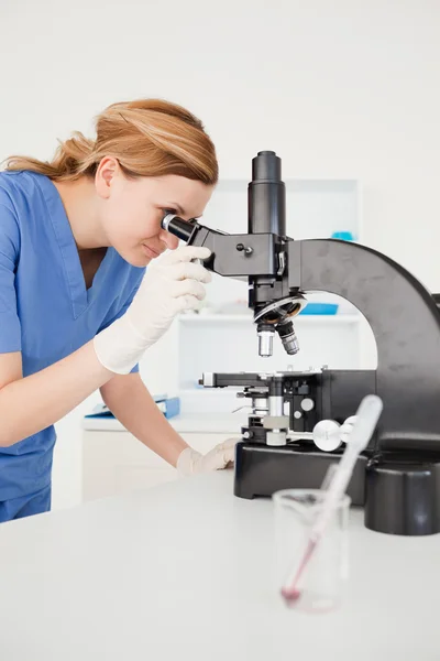Schattig vrouwelijke wetenschapper op zoek door een Microscoop — Stockfoto
