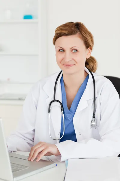 Médico sorridente trabalhando em seu laptop — Fotografia de Stock