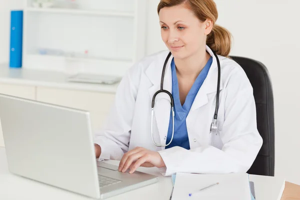 Привлекательная женщина-врач работает над своим ноутбуком — стоковое фото