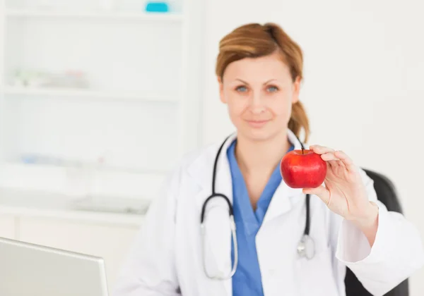Young female doctor showing a red apple — Stock Photo, Image