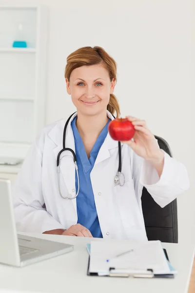 Söta kvinnliga läkare visar ett äpple till kameran — Stockfoto