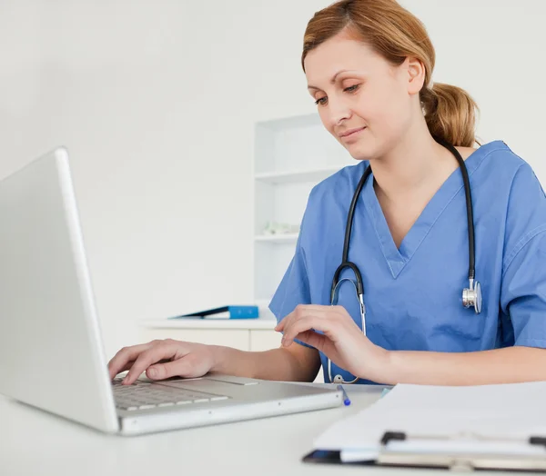 Jonge vrouwelijke arts werkzaam op haar laptop — Stockfoto