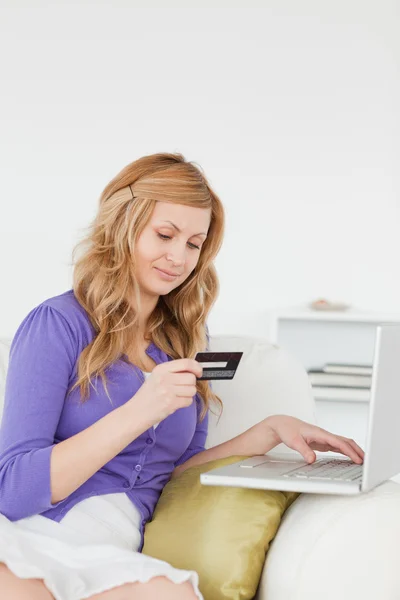 Gut aussehende Frau sitzt auf einem Sofa und zahlt — Stockfoto