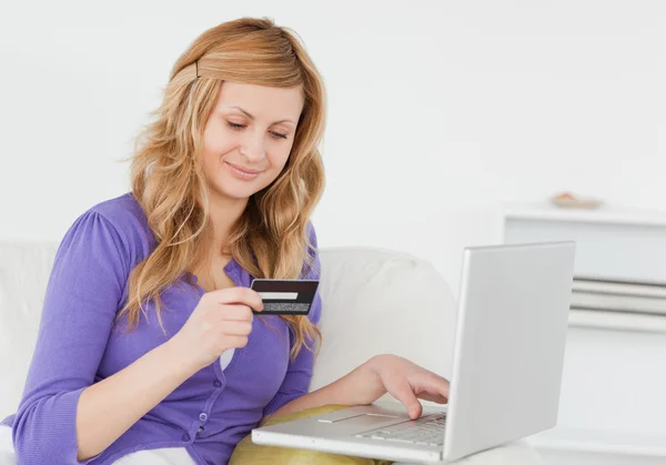 Attractive woman sitting on a sofa is going to make a payment on — Stock Photo, Image