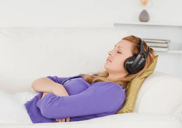 Mujer pelirroja de buen aspecto escuchando música mientras toma una — Foto de Stock