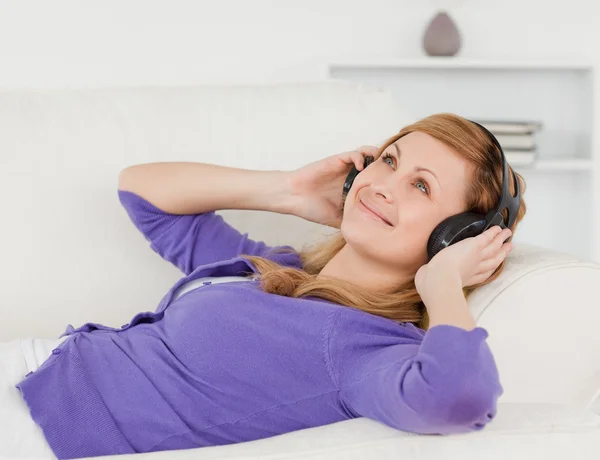 Beautiful red-haired woman listening to music and enjoying the m — Stock Photo, Image