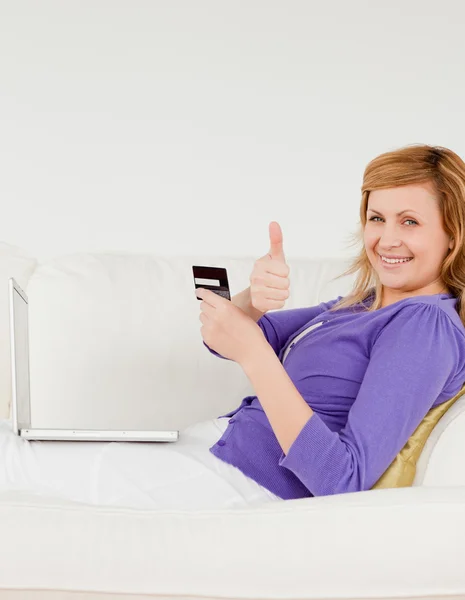 Boldog vörös hajú nő használ egy laptop és egy telefon fekve — Stock Fotó