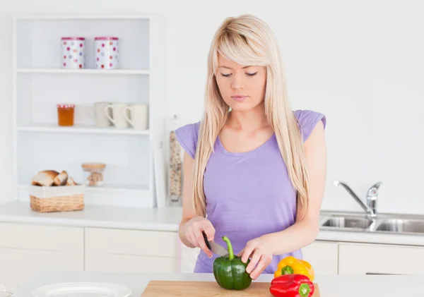 Улыбающаяся блондинка режет овощи в современном интерьере кухни — стоковое фото