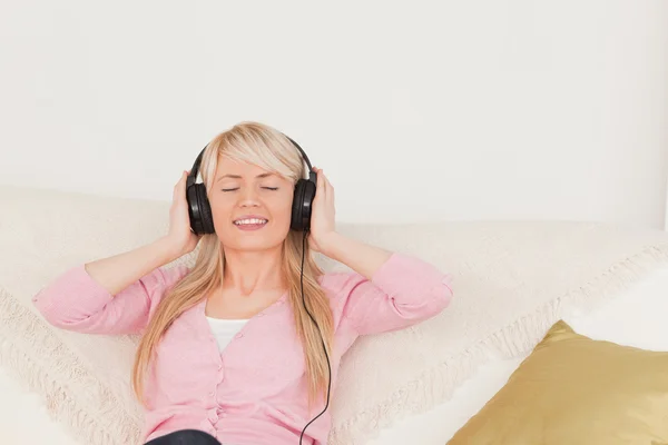Красивая женщина слушает музыку в наушниках, пока си — стоковое фото